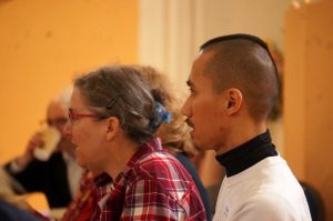 A side profile photograph of a man and woman singing and looking towards a song leader. 