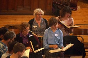 Four seated alto singers viewed from the church balcony.