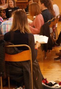 View of seated singers from between the tenor and treble section. 