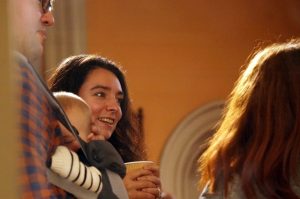 A candid photo of a woman smiling while chatting to other singers. 