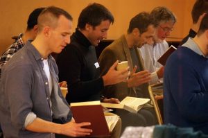 A side phot showing several men singing bass from their books.